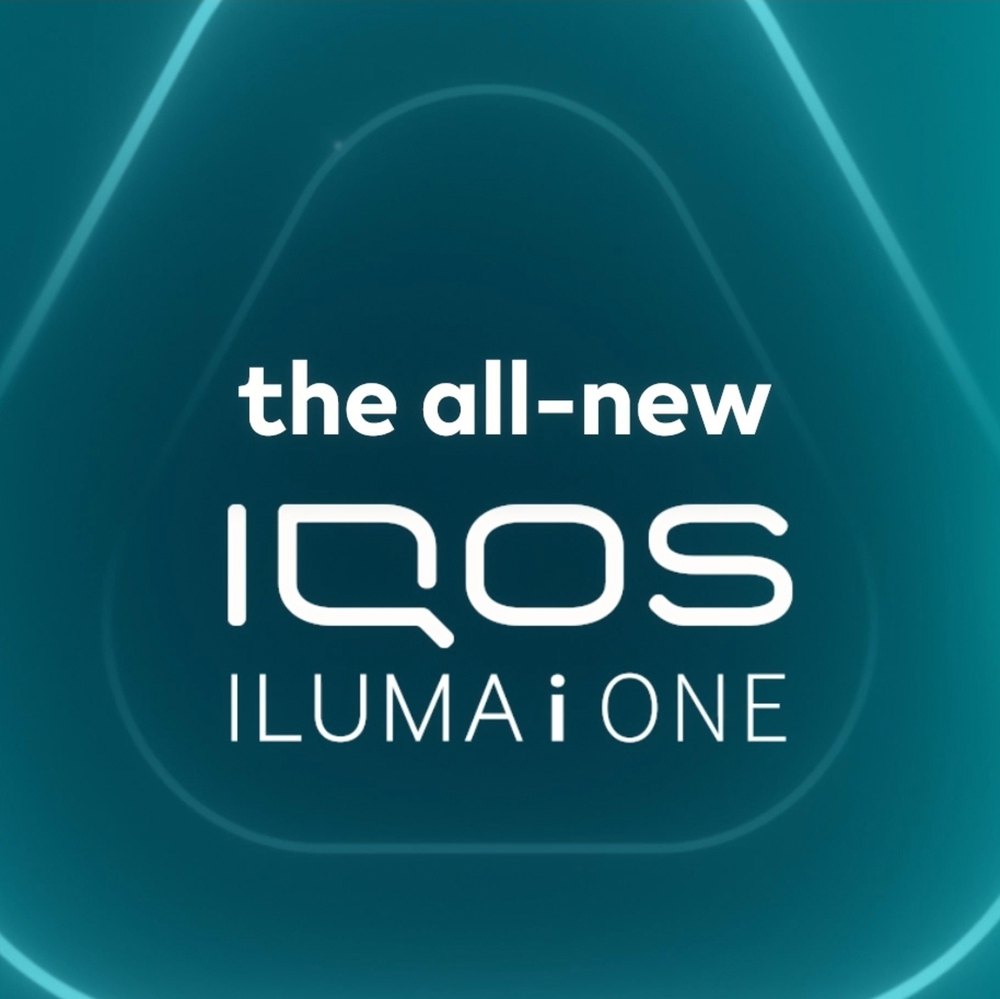 A person holding an IQOS Device in front of a building